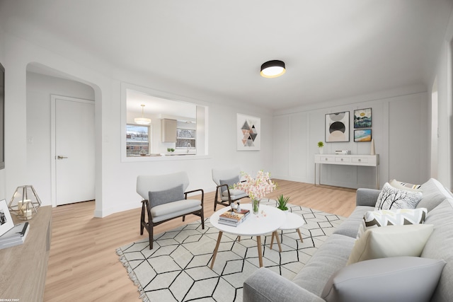 living area featuring light wood-type flooring and arched walkways