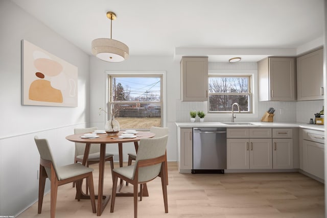 kitchen featuring dishwasher, a sink, gray cabinets, and a wealth of natural light