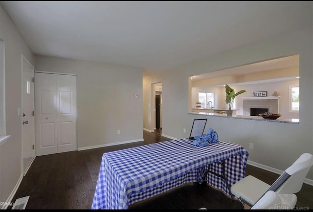 bedroom featuring visible vents, a fireplace, baseboards, and wood finished floors