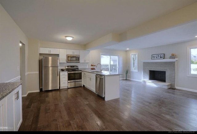 kitchen with a peninsula, appliances with stainless steel finishes, white cabinets, and dark wood-type flooring