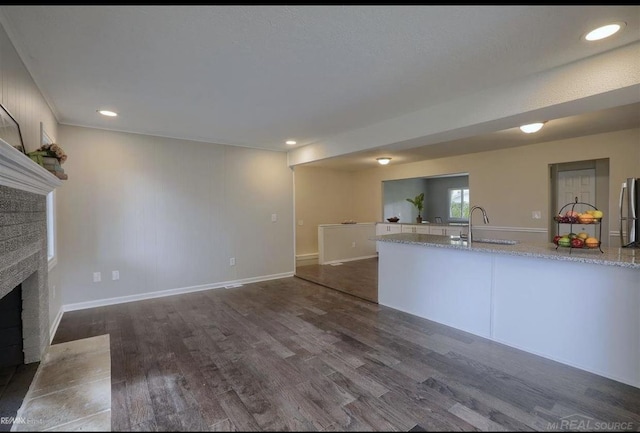 kitchen with freestanding refrigerator, dark wood-style flooring, a fireplace, and a sink