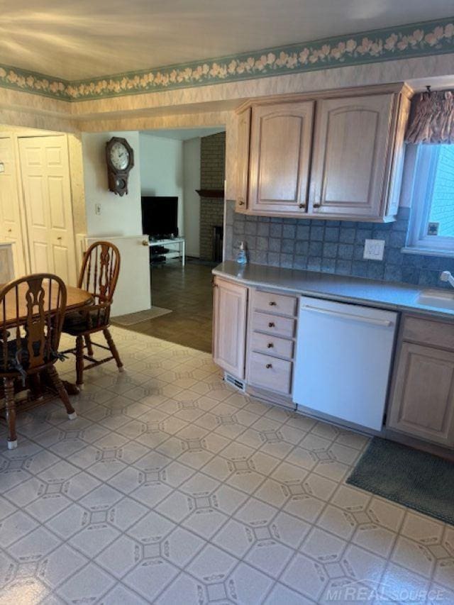 kitchen featuring a sink, light floors, decorative backsplash, and dishwasher