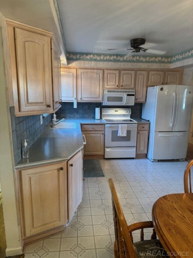 kitchen with a ceiling fan, white appliances, light brown cabinets, and a sink