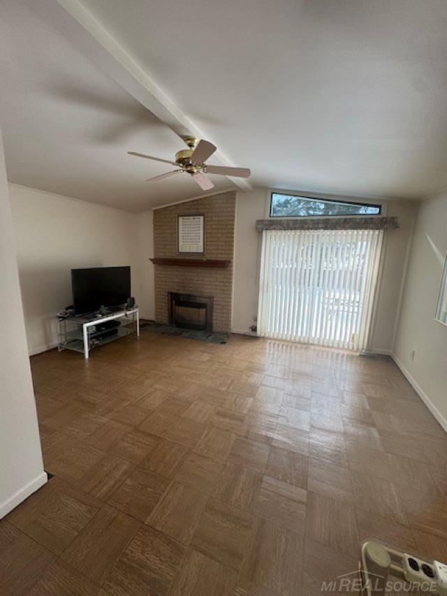 unfurnished living room with lofted ceiling with beams, ceiling fan, a fireplace, and baseboards