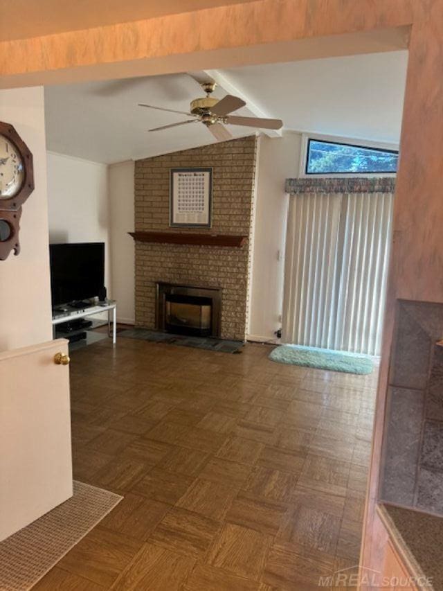 unfurnished living room featuring a fireplace, lofted ceiling with beams, and ceiling fan