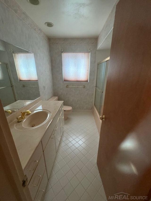 bathroom featuring toilet, a shower with door, vanity, and tile patterned floors