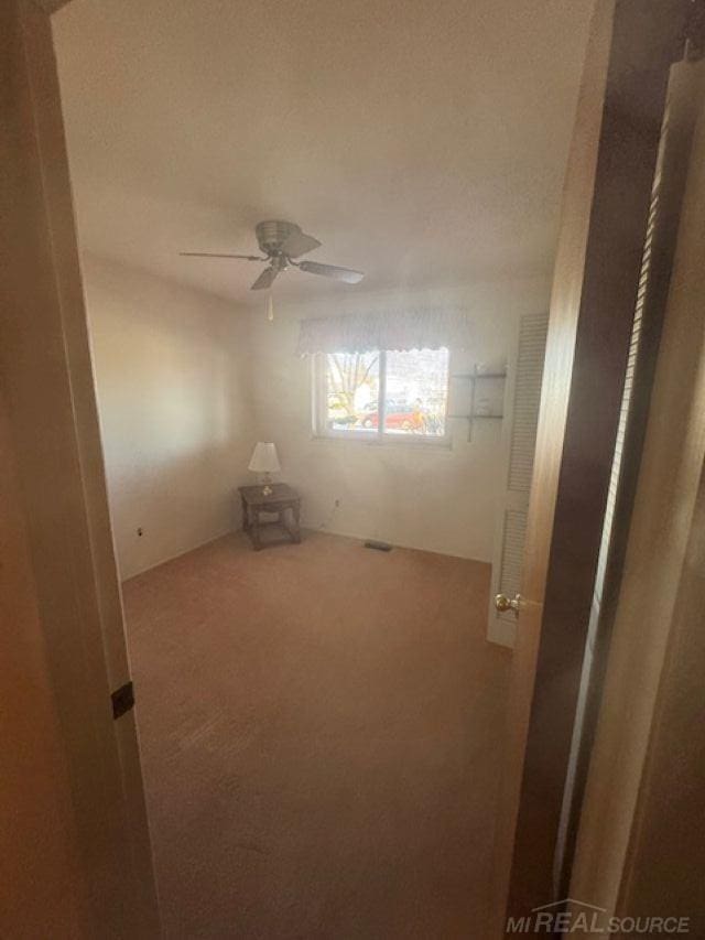 carpeted empty room featuring a ceiling fan