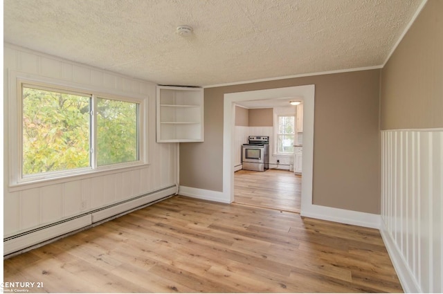 spare room with ornamental molding, light wood finished floors, baseboard heating, and a textured ceiling