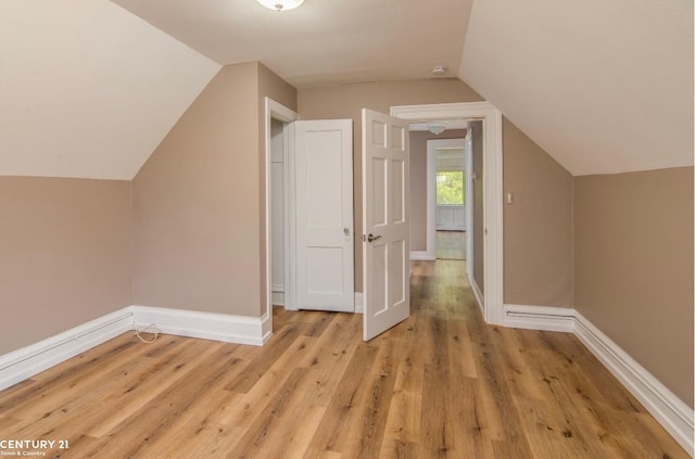 bonus room featuring light wood-style flooring, baseboards, and vaulted ceiling