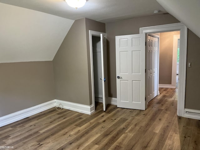 additional living space with lofted ceiling, baseboards, and wood finished floors