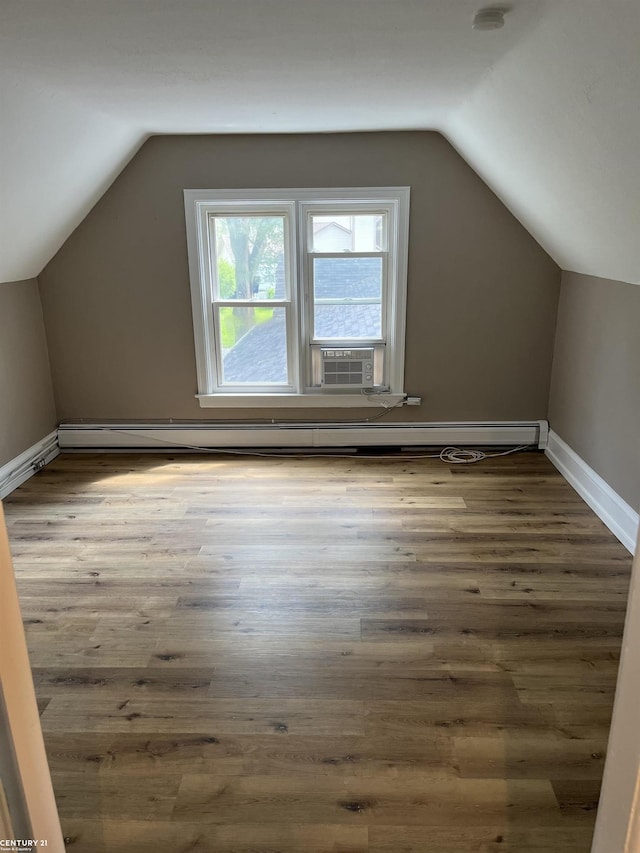 additional living space featuring lofted ceiling, a baseboard radiator, baseboards, and wood finished floors