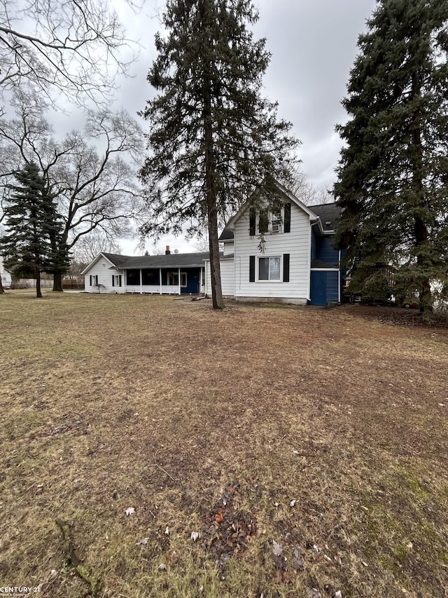 rear view of property featuring a lawn and a sunroom