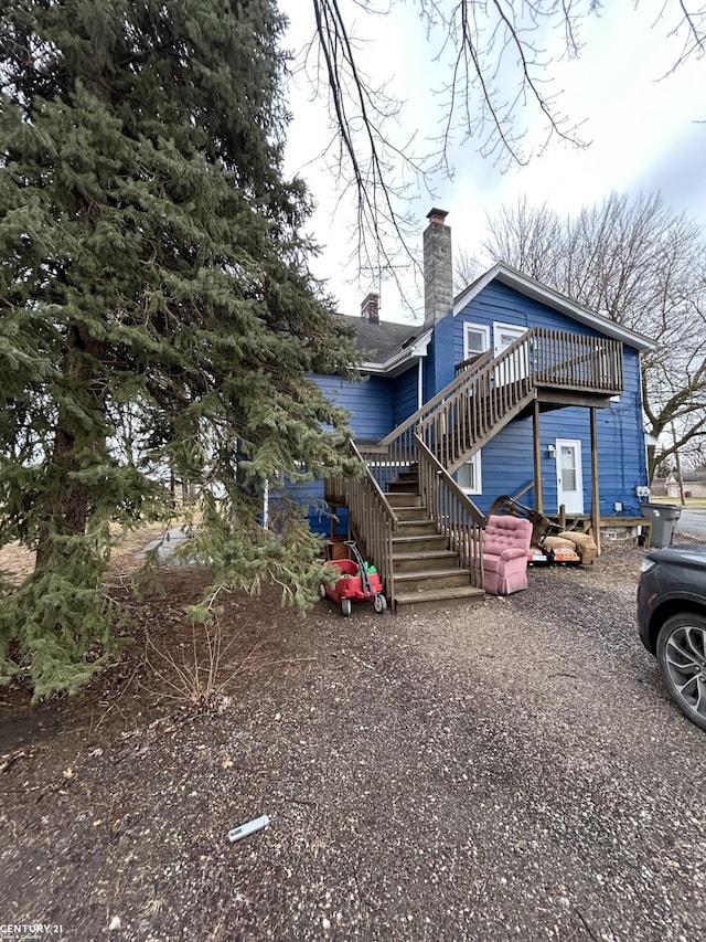 view of front of house with stairway, a chimney, and a wooden deck