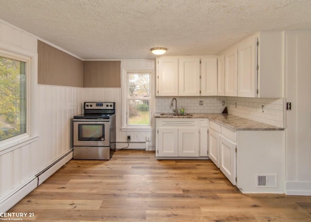 kitchen featuring light wood finished floors, visible vents, stainless steel range with electric cooktop, a baseboard heating unit, and a sink