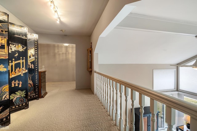 hallway featuring rail lighting, carpet, and vaulted ceiling