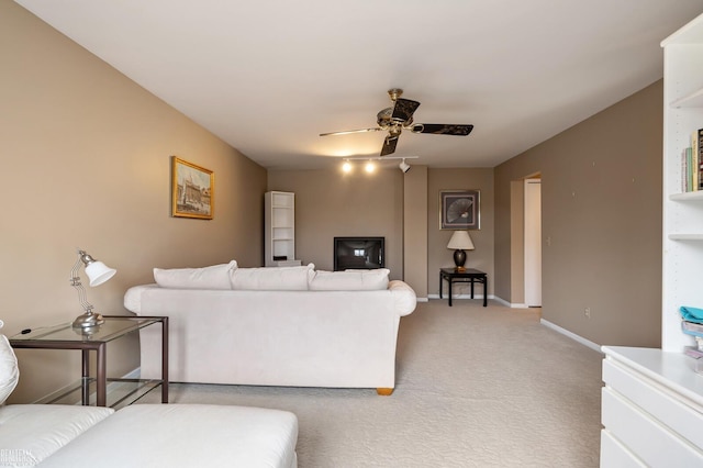 living area featuring ceiling fan, baseboards, and light colored carpet