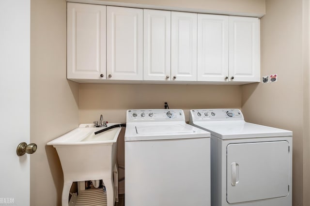 clothes washing area with cabinet space, washing machine and dryer, and a sink