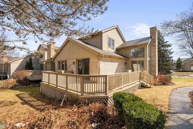 rear view of property with a wooden deck, a chimney, and brick siding