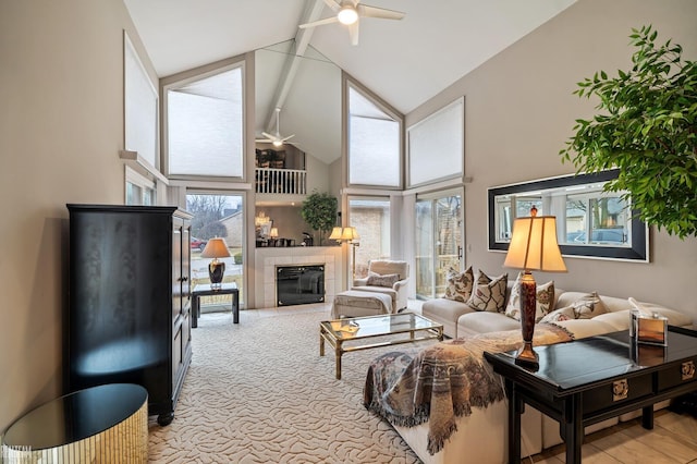 living area featuring ceiling fan, beamed ceiling, a wealth of natural light, and a tile fireplace