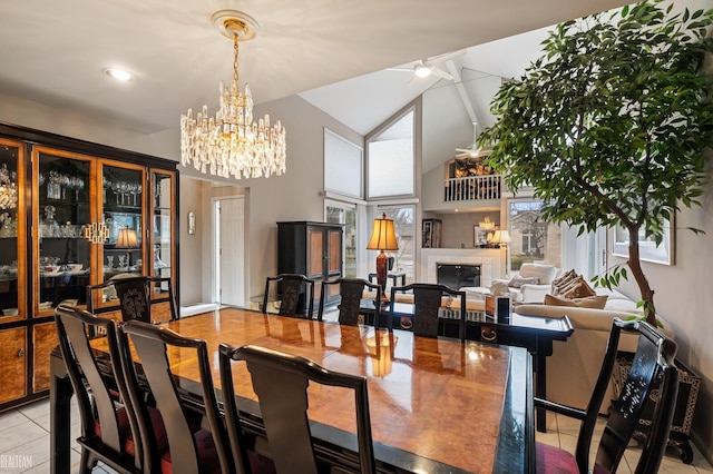 dining room with light tile patterned floors, high vaulted ceiling, a tile fireplace, a healthy amount of sunlight, and an inviting chandelier