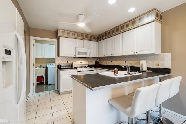 kitchen with white appliances, white cabinets, ceiling fan, a peninsula, and a sink