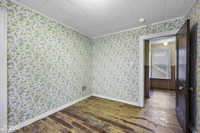 spare room with ornamental molding, dark wood-style flooring, baseboards, and wallpapered walls