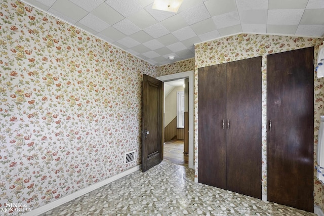 unfurnished bedroom featuring wallpapered walls, baseboards, visible vents, and vaulted ceiling