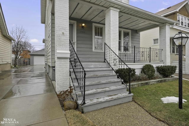 entrance to property featuring a garage, covered porch, and brick siding