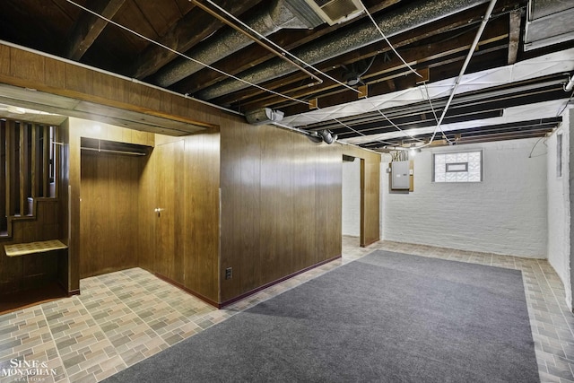 basement featuring wood walls, brick wall, and electric panel