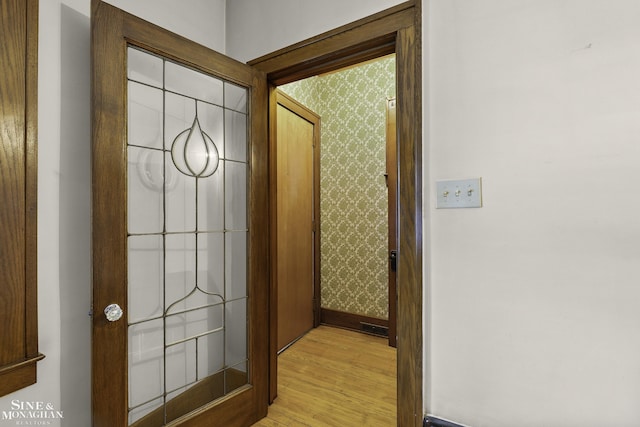 doorway to outside with baseboards, light wood-style flooring, and wallpapered walls