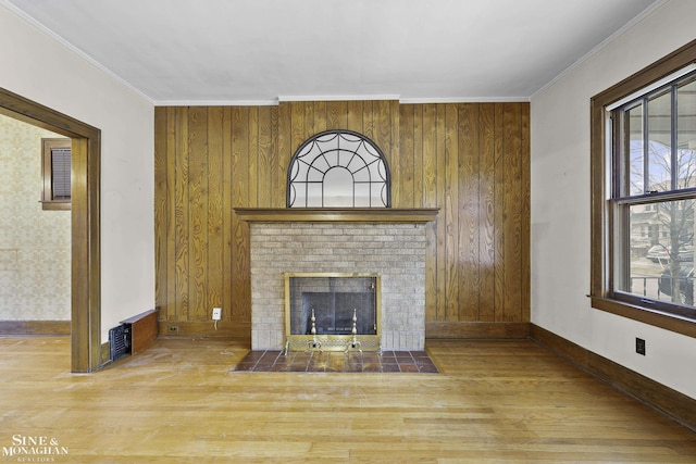 unfurnished living room featuring ornamental molding, a fireplace, baseboards, and wood finished floors