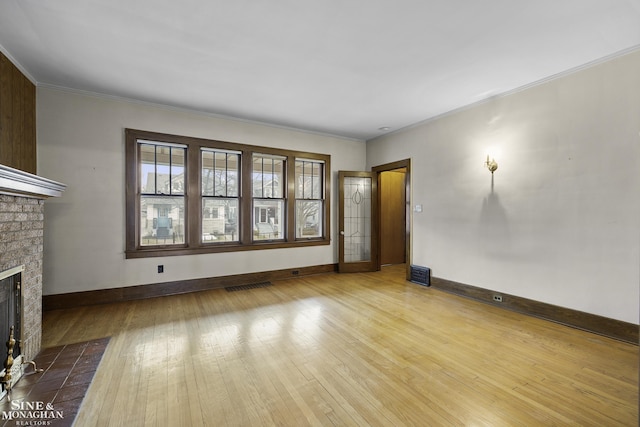 unfurnished living room featuring visible vents, baseboards, hardwood / wood-style flooring, crown molding, and a brick fireplace