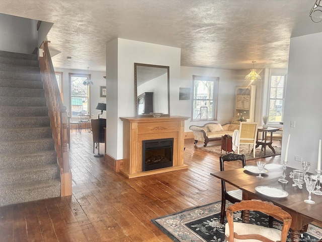 living area featuring a textured ceiling, dark wood-type flooring, stairway, and a fireplace