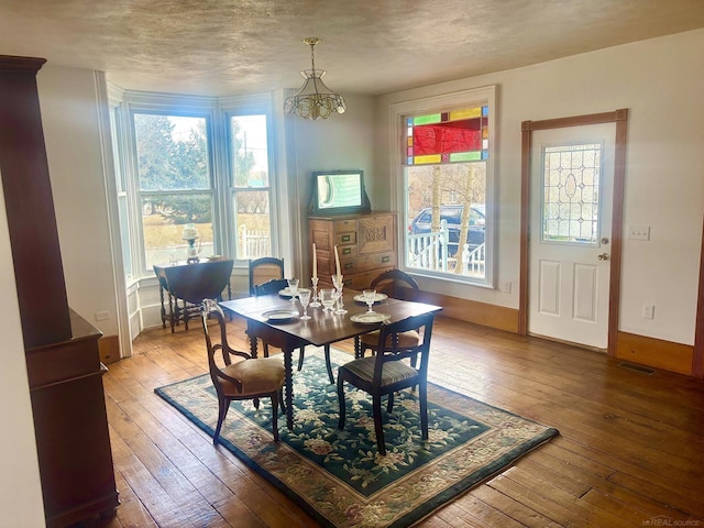 dining area featuring wood-type flooring, a textured ceiling, visible vents, and a wealth of natural light