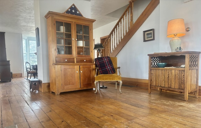 living area with stairs, wood-type flooring, and baseboards