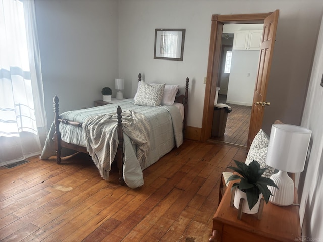 bedroom with baseboards, visible vents, and hardwood / wood-style floors