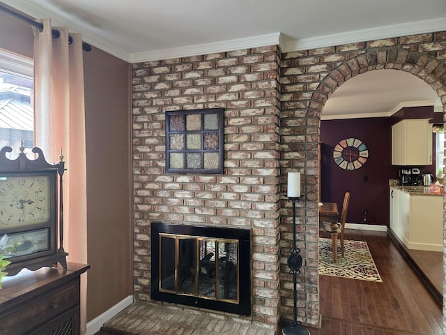 living room with ornamental molding, arched walkways, baseboards, and wood finished floors