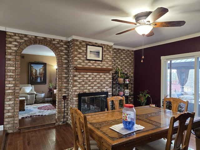 dining room featuring ornamental molding, a ceiling fan, a fireplace, and hardwood / wood-style flooring