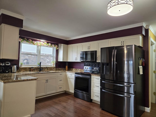 kitchen with dark stone counters, stainless steel appliances, a sink, and white cabinetry