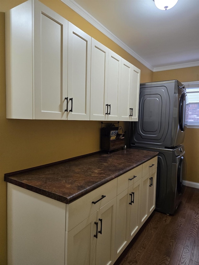 laundry room with cabinet space, baseboards, dark wood-style floors, stacked washer / drying machine, and crown molding