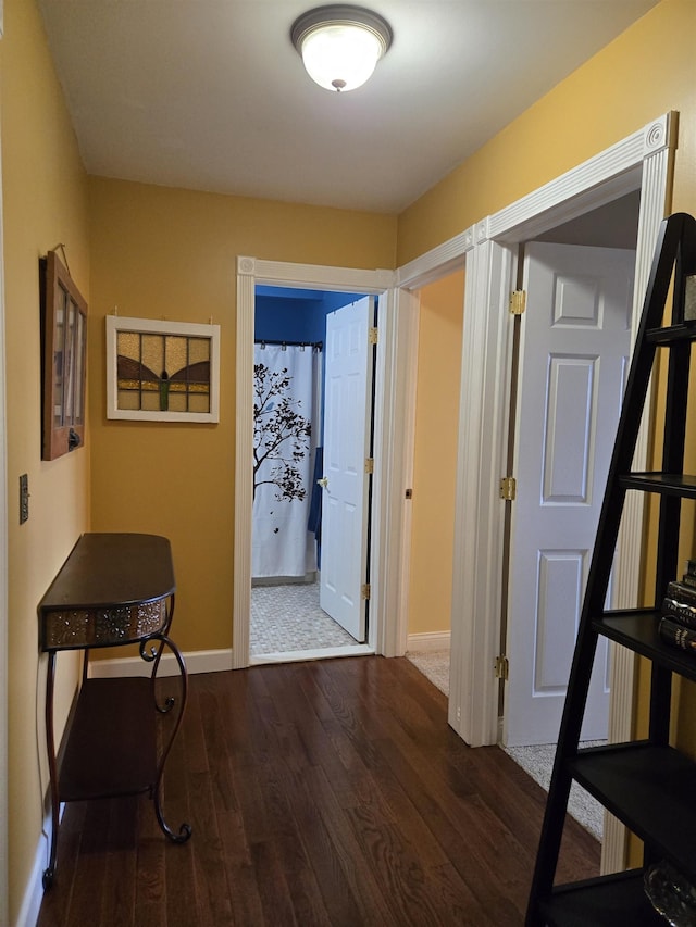 corridor featuring wood-type flooring and baseboards