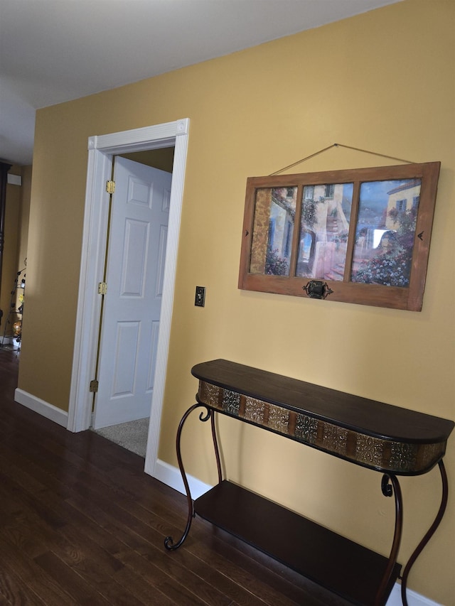 corridor featuring baseboards and dark wood finished floors