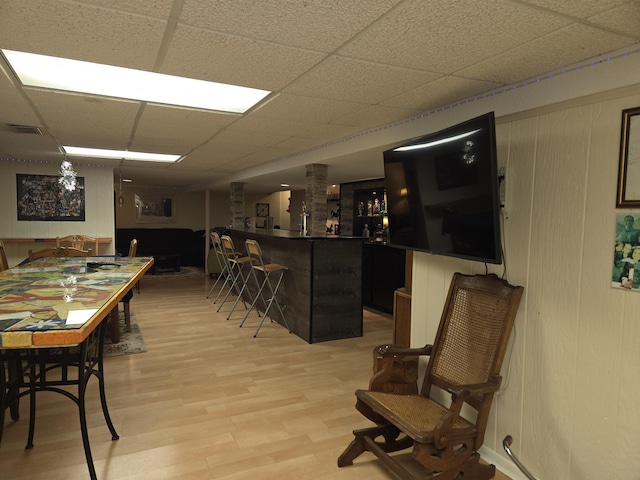 bar with a drop ceiling, a dry bar, light wood-type flooring, and visible vents