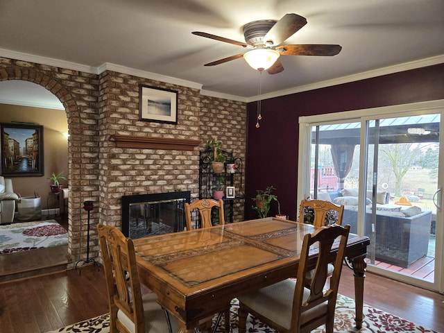 dining area featuring a fireplace, crown molding, hardwood / wood-style floors, and ceiling fan