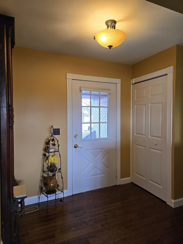 doorway featuring dark wood-style flooring and baseboards