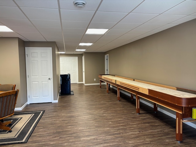 recreation room with baseboards, a drop ceiling, and dark wood-type flooring