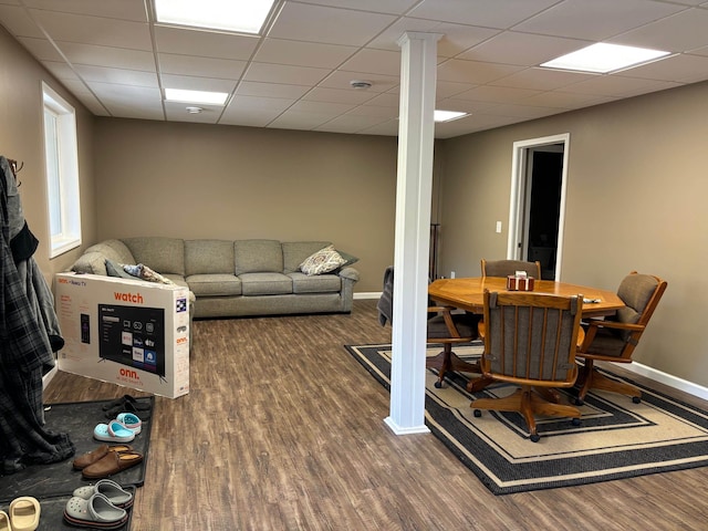 living area with ornate columns, a drop ceiling, wood finished floors, and baseboards