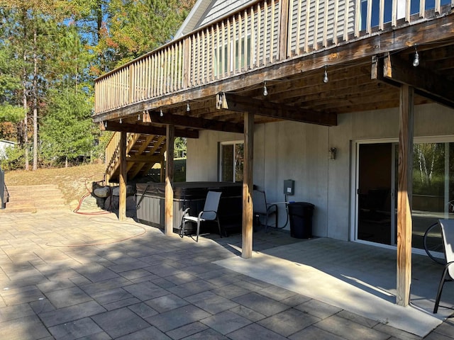 view of patio / terrace with stairway, a carport, a hot tub, and a deck