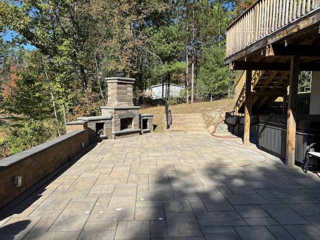 view of patio / terrace featuring an outdoor stone fireplace, a hot tub, and stairs