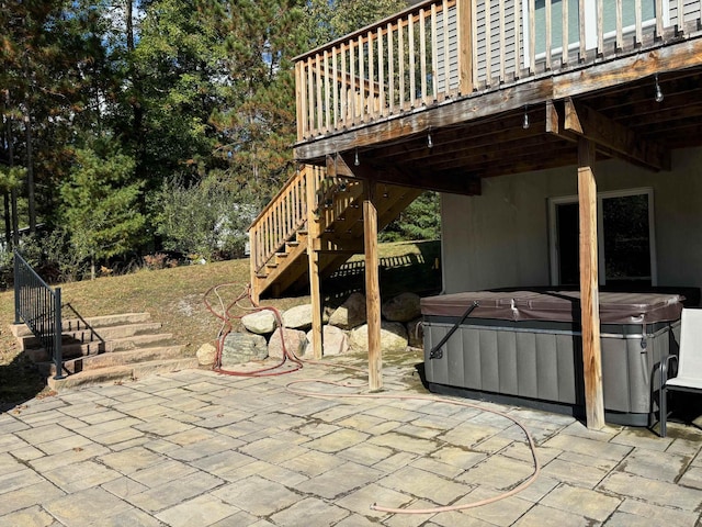 view of patio featuring a hot tub, stairs, and a deck